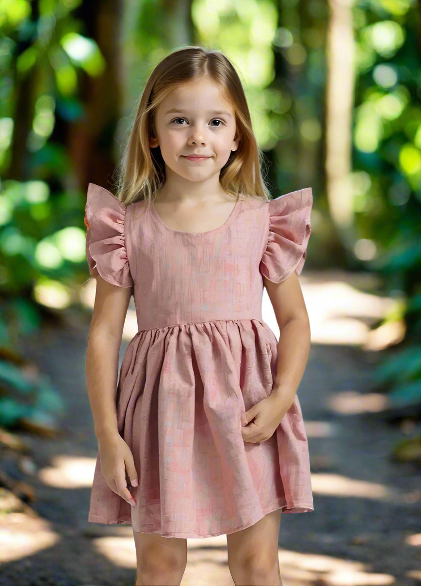 girl wearing a pink dress and standing into the jungle